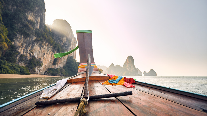A longtail boat with mountains in the background of the ocean in Thailand. 