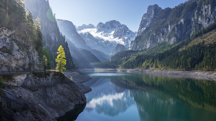 A lake sitting down in a valley between very large mountains in Austria's Alps 