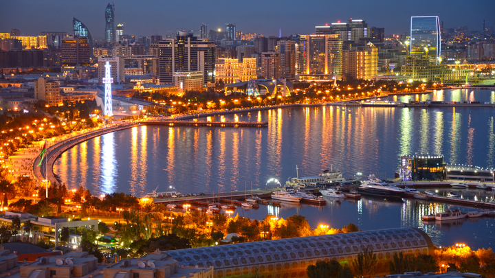 Azerbaijan at night with buildings lit up along the water front.