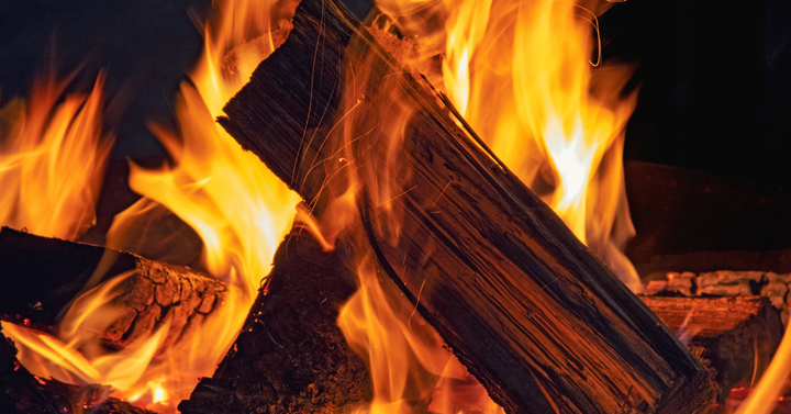 Campfire showing wood on fire with flames shooting up through the wood.