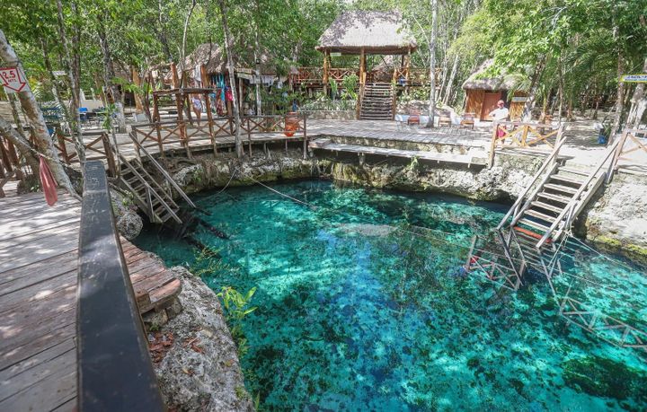 A beautiful Cenote in Tulum, Mexico with stairs leading down into the clear blue Caribbean waters.