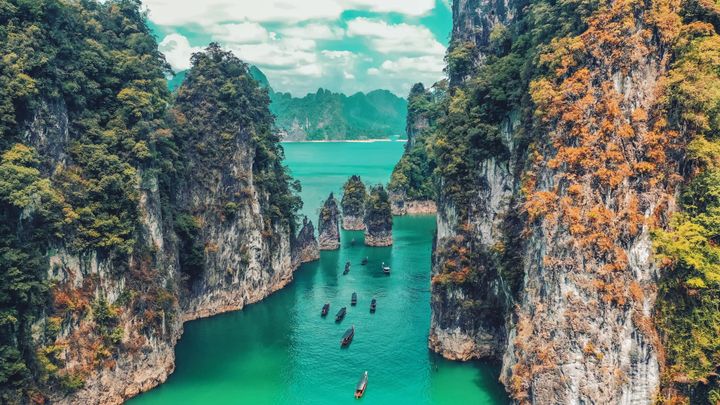 Boats passing through a canyon on a beautiful emerald green lake.