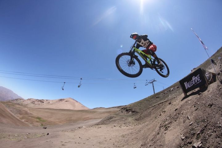 A person riding a mountain bike and waring protective gear while going down a dirt mountain trail.