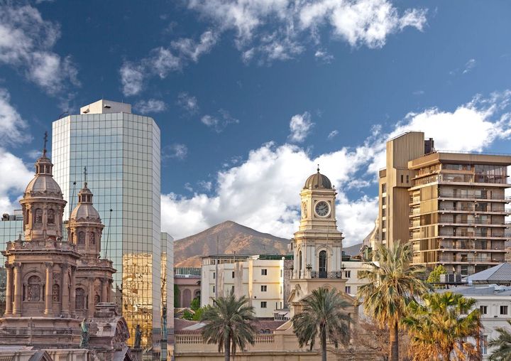 View of old and modern buildings surrounded by a few palm trees in Santiago, Chile.