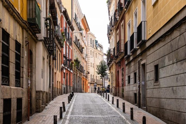 A quiet cobblestone street in Madrid’s Malasaña neighborhood, lined with colorful buildings and wrought-iron balconies.