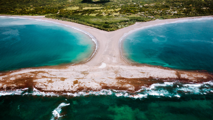 Aerial view of the Whale Tail sandbar at Playa Uvita in Marino Ballena National Park, Costa Rica, showing two symmetrical beaches extending into the turquoise ocean.