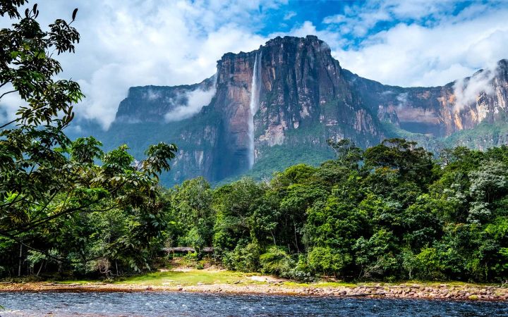 A beautiful river with a waterfall coming off a mountain in Suriname surrounded by rain forest.