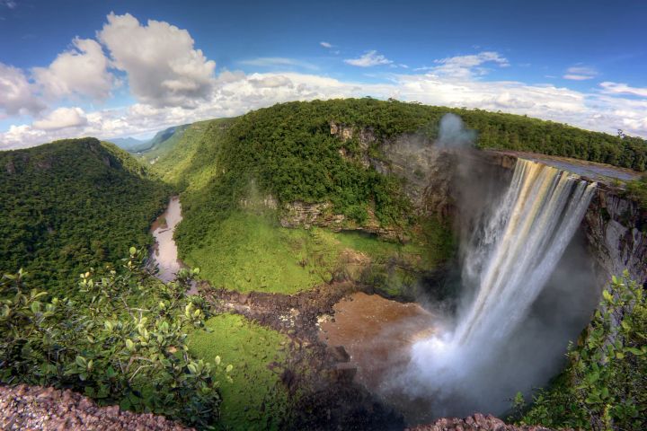 Waterfall in Guyana surrounded by lush green tropical trees.