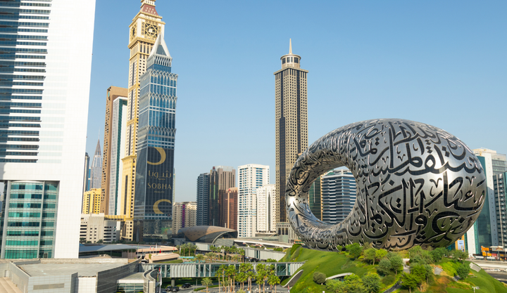 Futuristic skyline view of Dubai featuring the Museum of the Future, a torus-shaped building with Arabic calligraphy.