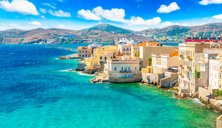 Beautiful ocean front buildings at Ermoupoli, Syros, Greece with mountains in the background.