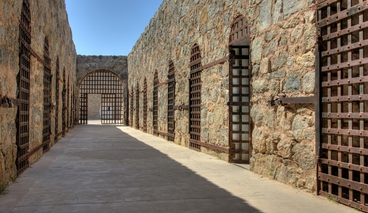 Inside of the cell block at Yuma Territorial Prison State Historic Park showing metal doors on the front of the cells. 