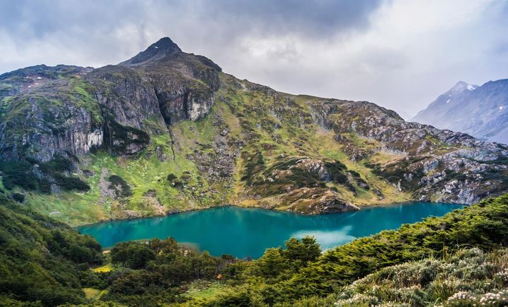 Laguna Esmeralda is a beautiful blue lake surrounded by mountains and clouds in the sky.