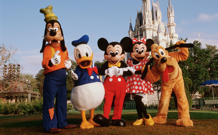 Goofy, Donald Duck, Mickey Mouse, Mini Mouse standing in front of the Disney Castle at Disney World Orlando.