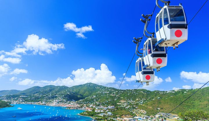 Heavensight Cable Car St. Thomas shows white gondola going down from the mountain to the ocean.