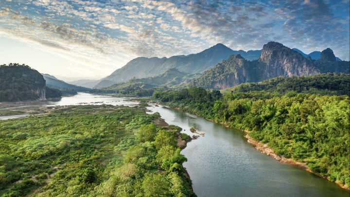 A river in Laos and mountains in the background on a parlay cloudy day.