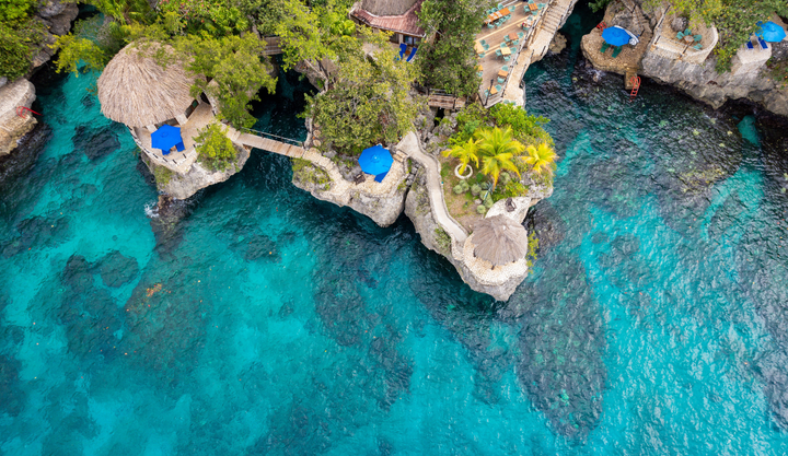 Ariel view of a resort sitting on the cliff side of the beautiful blue Caribbean sea at Rockhouse hotel in Negril, Jamaica.