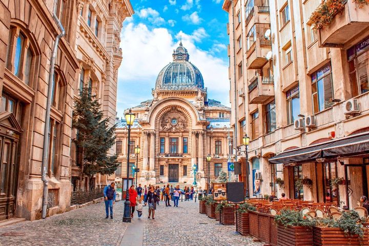 People walking in Bucharest old town cobble stone streets and historic buildings.