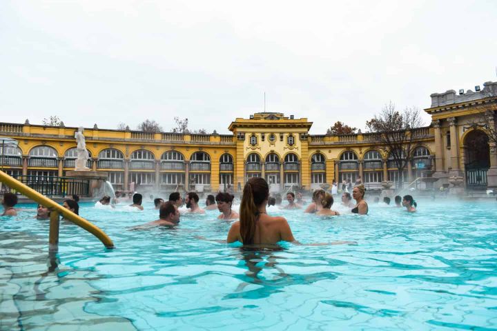 People in the large outdoor thermanl hotturbs in Budapest.