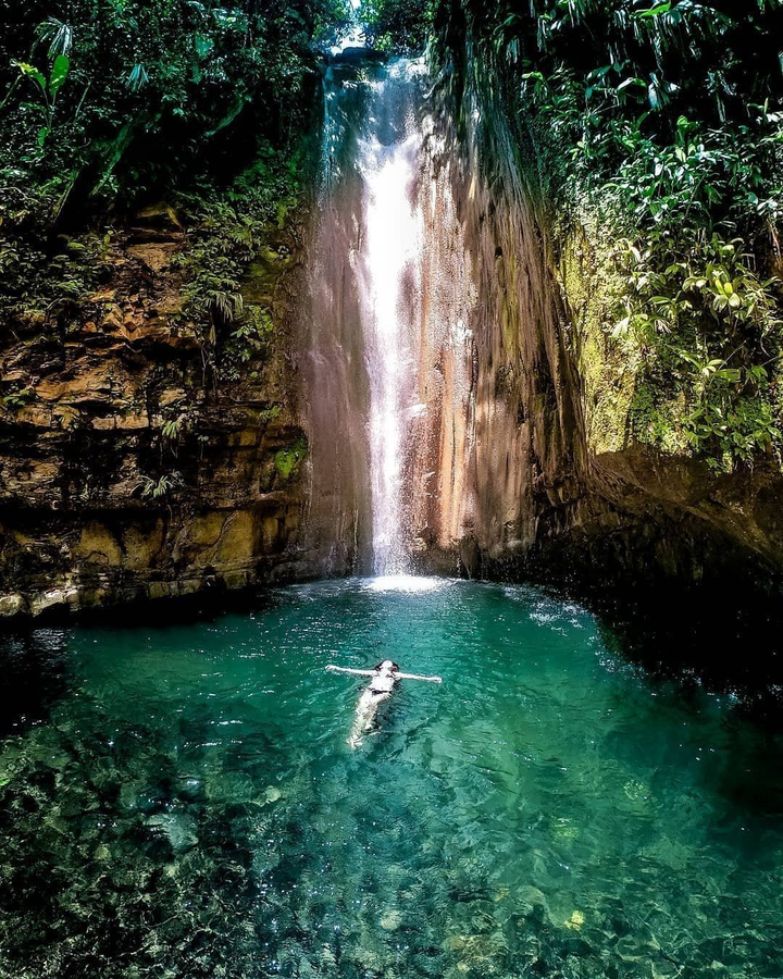 Floating in pool of clear waters at the base of a waterfall in Colombia.