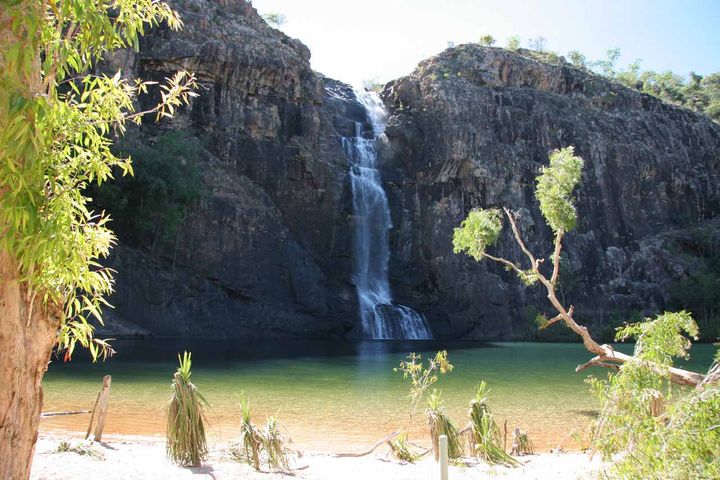 A waterfall in Australia flowing into a pool of water next to a beach.