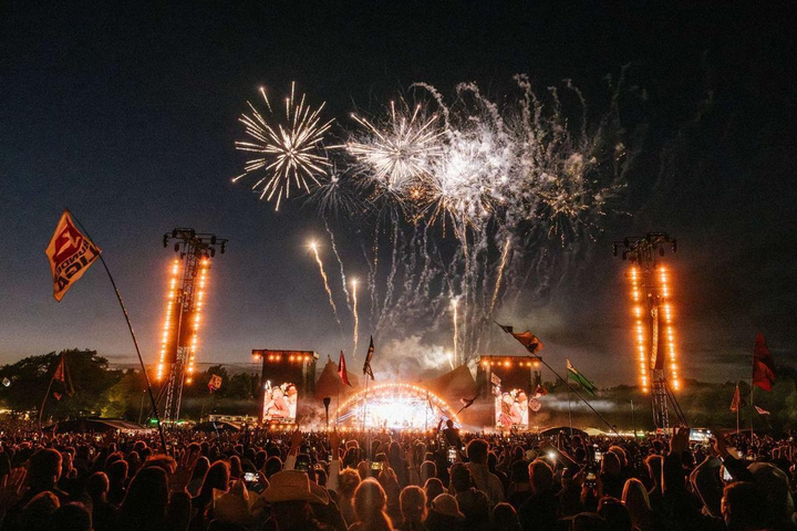 Fireworks being shot off and lighting up the sky with thousands of people below at Roskilde Festival.