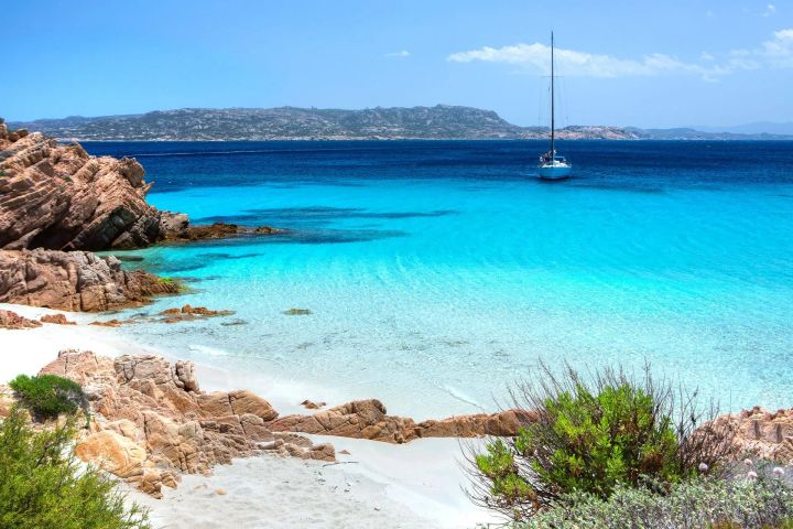 A sailboat anchored at a beautiful beach in Sardinia. 