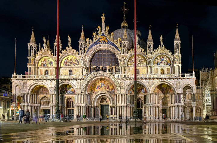 San Marco Basilica in Venice, Italy at night lit up with lights.