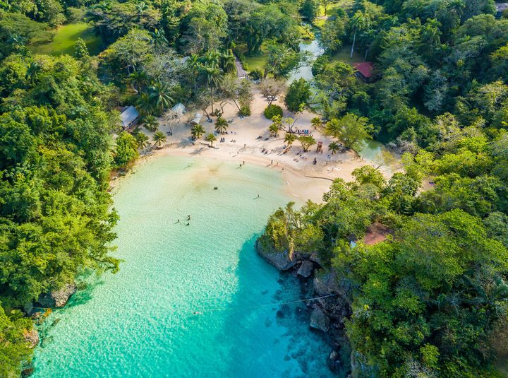 View of a beautiful beach in Jamaica that is a secluded and surrounded by trees on each side.