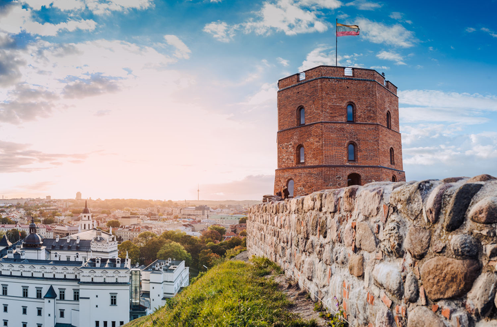 Old rock wall with a castle like building over looking a city in Lithuania.