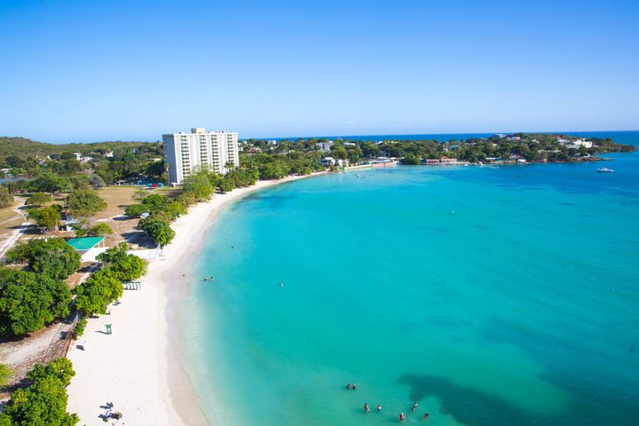 White sandy beach with clear blue waters in Puerto Rico with a large high rise resort in the background.