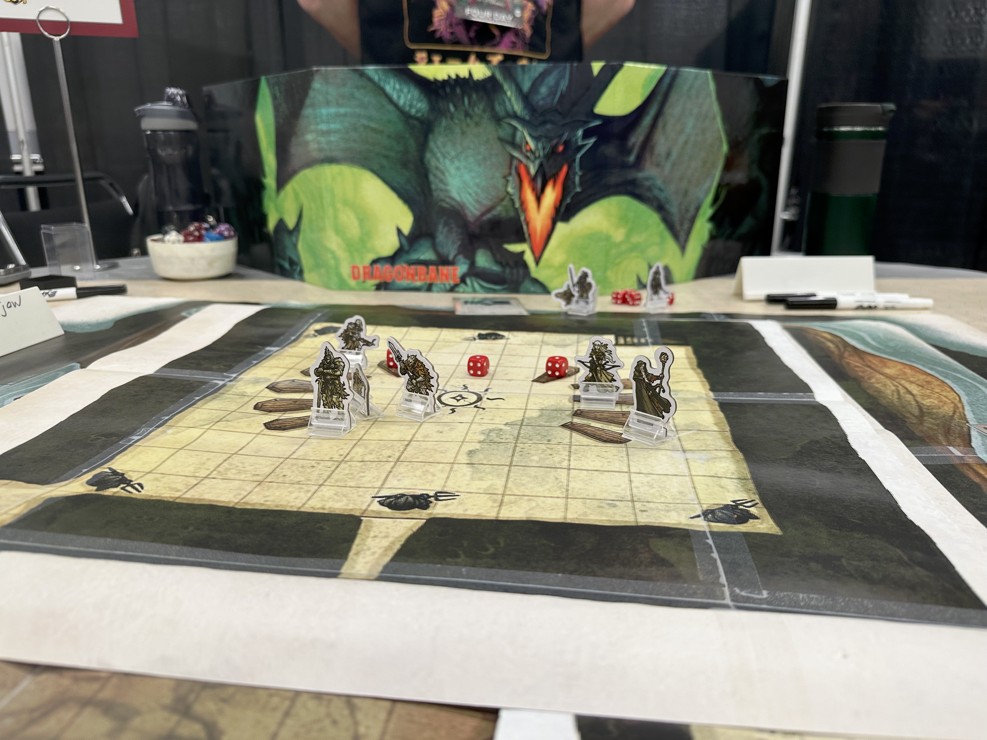 A Dragonbane GM screen and a battle map with pawns on it.