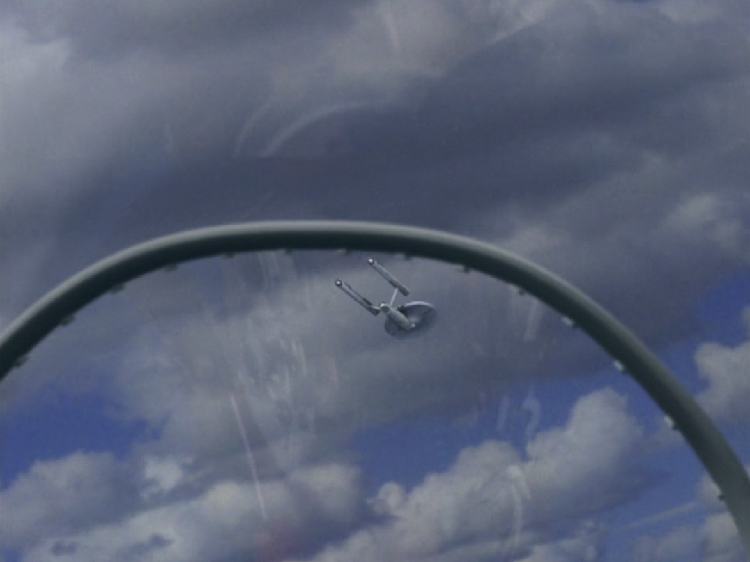 USS Enterprise in a blue sky seen through the glass of a fighter pilot