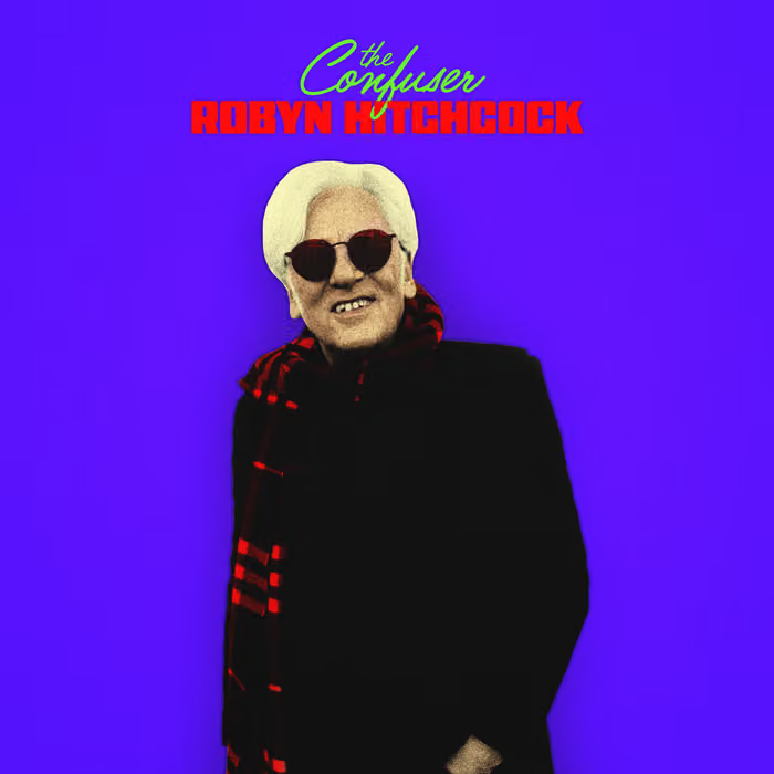 Cover shows Hitchcock in black overcoat, sunglasses and red and black checkered scarf against a purple background.