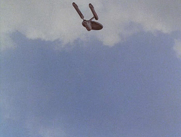 The Enterprise superimposed on a blue earth sky with white clouds.