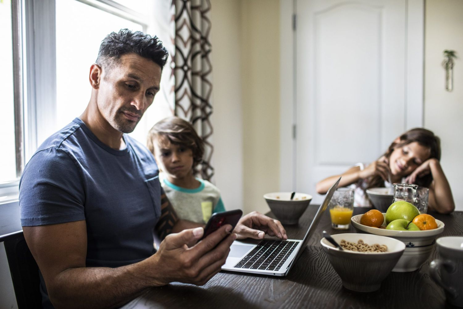 dad using phone - Authoritative vs Authoritarian Parenting