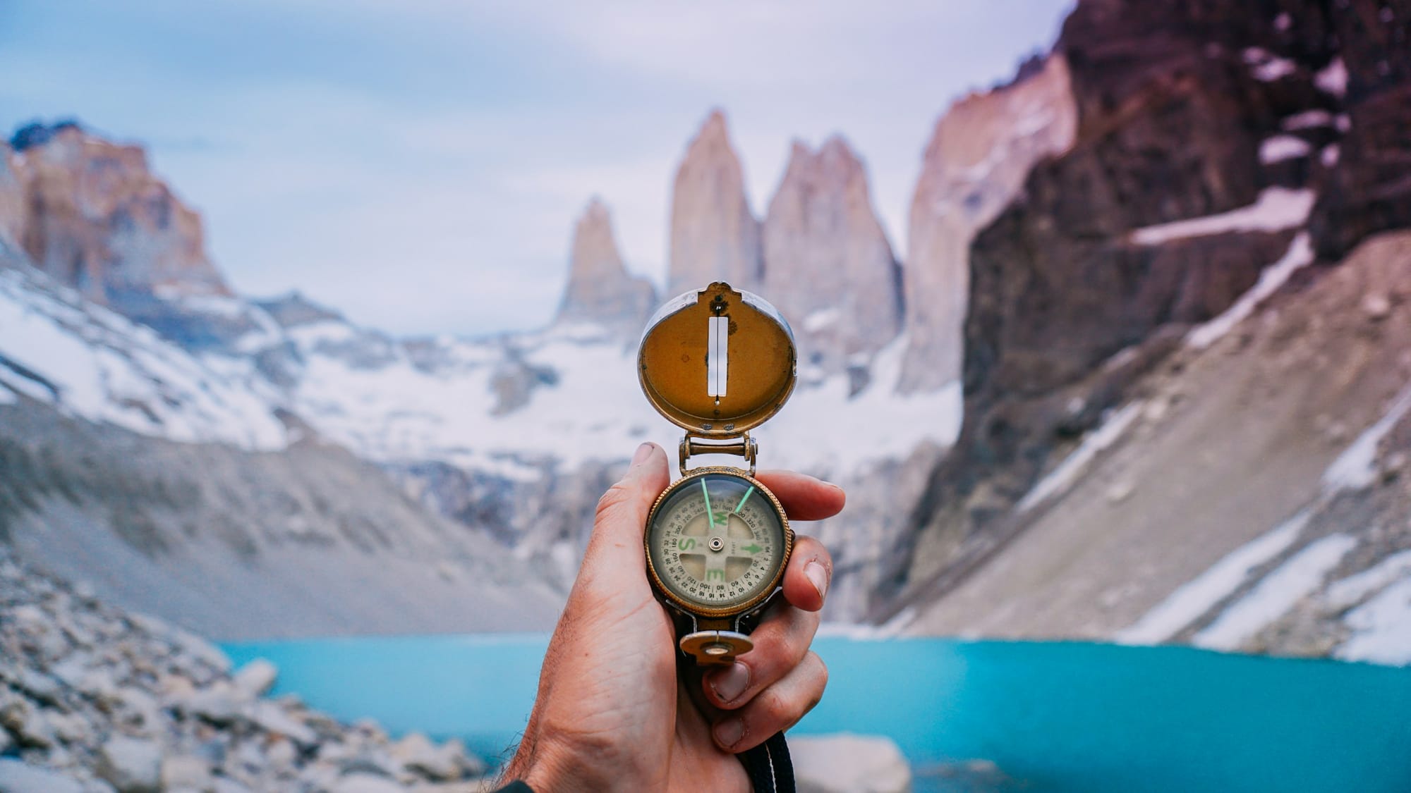 Hand holding a compass in a glacial mountain scene
