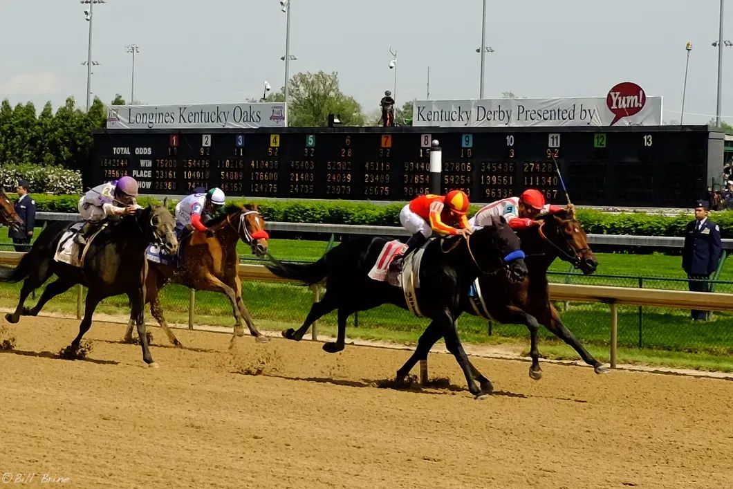 Thurby horse race at Churchill Downs with jockeys and scoreboard – a popular day for locals during Kentucky Derby week.