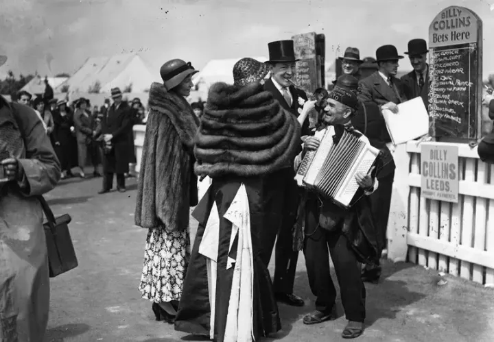 Vintage scene at Royal Ascot, with men in top hats and women in fur stoles and hats, socialising by the bookmakers.