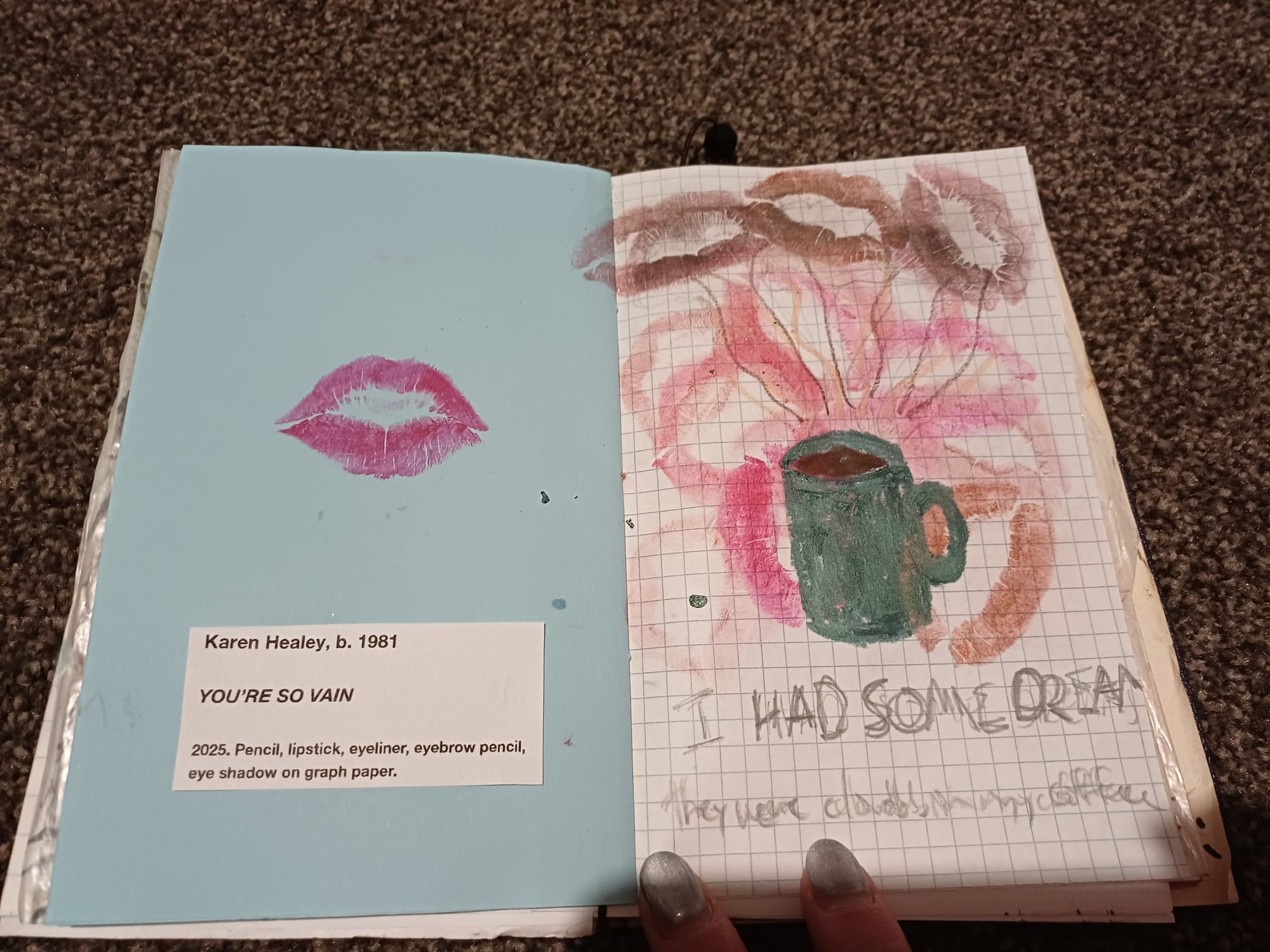 Right hand page: Lip prints in a variety of colours form a background to a sketched coffee cup from which steam is rising and resolving into lipstick clouds. Text below reads "I HAD SOME DREAMS they were clouds in my coffee". Left page: a single lip print and below it a printed label in the style of an art gallery reading: Karen Healey, b.1981. YOU'RE SO VAIN. 2025. Pencil, lipstick, eyeliner, eyebrow pencil, eye shadow on graph paper."