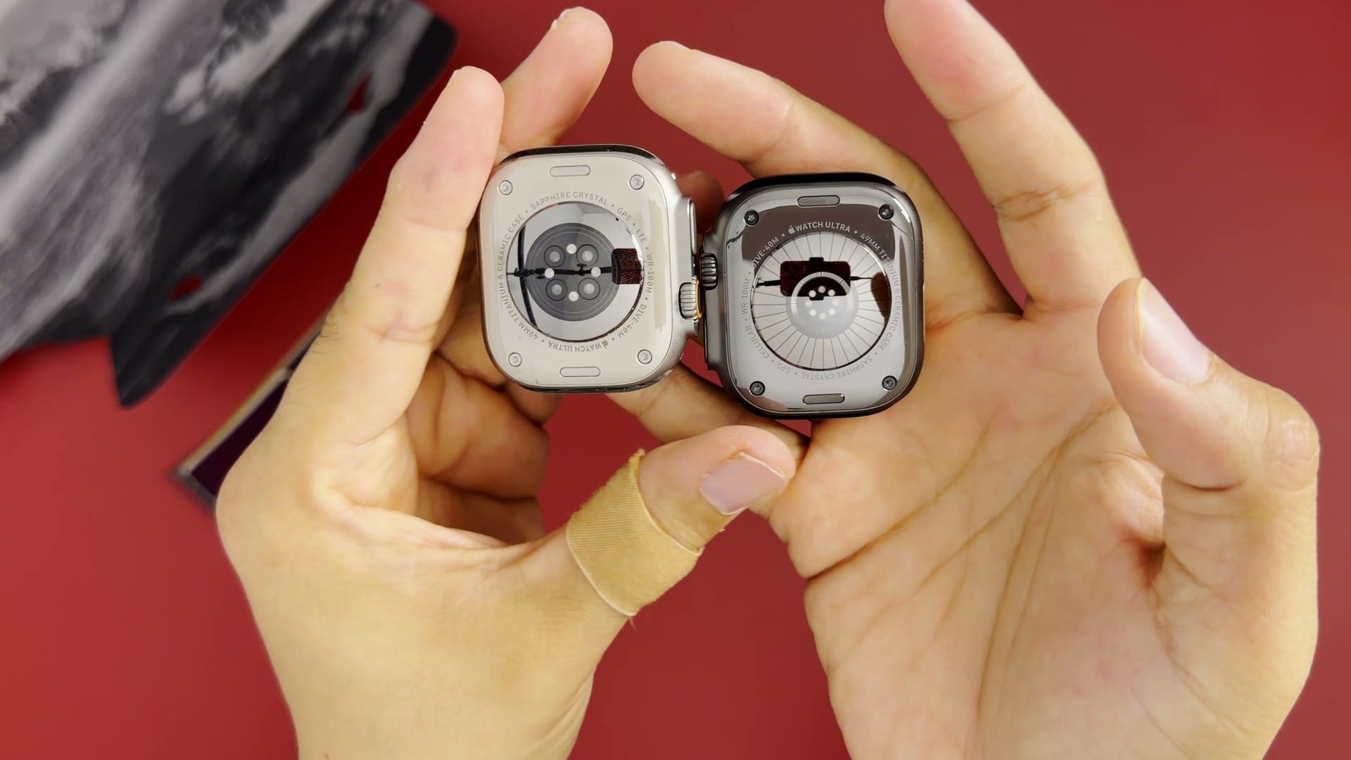 Backs of the Apple Watch Ultra 2 and Ultra 4 held side by side, showing the redesigned Ultra 4 sensor