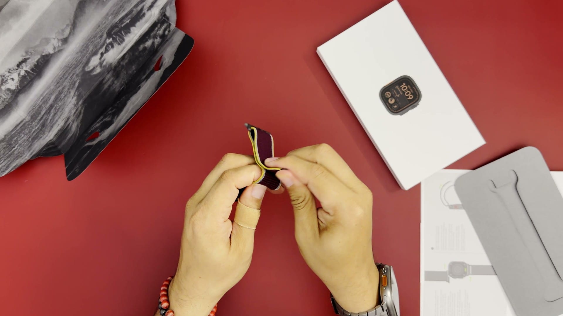 Burgundy nylon band being unpacked next to the Apple Watch Ultra 4 box