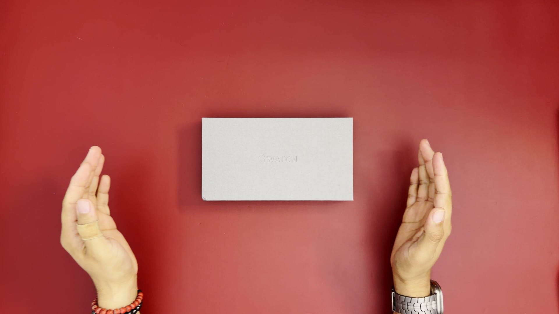 Apple Watch Ultra 4 box on a red mat between two hands