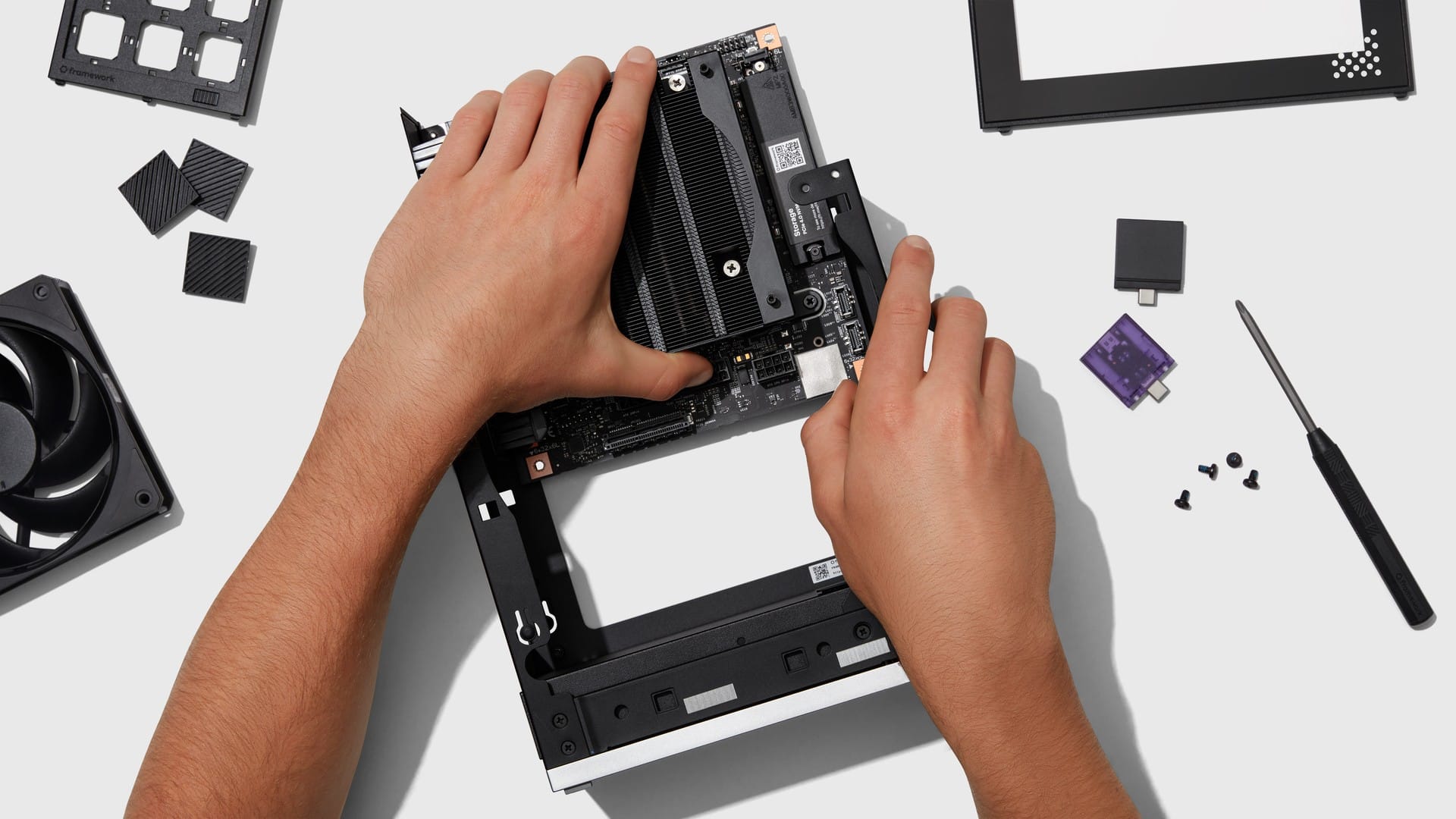 Hands fitting the Framework Desktop Mini-ITX mainboard into its case