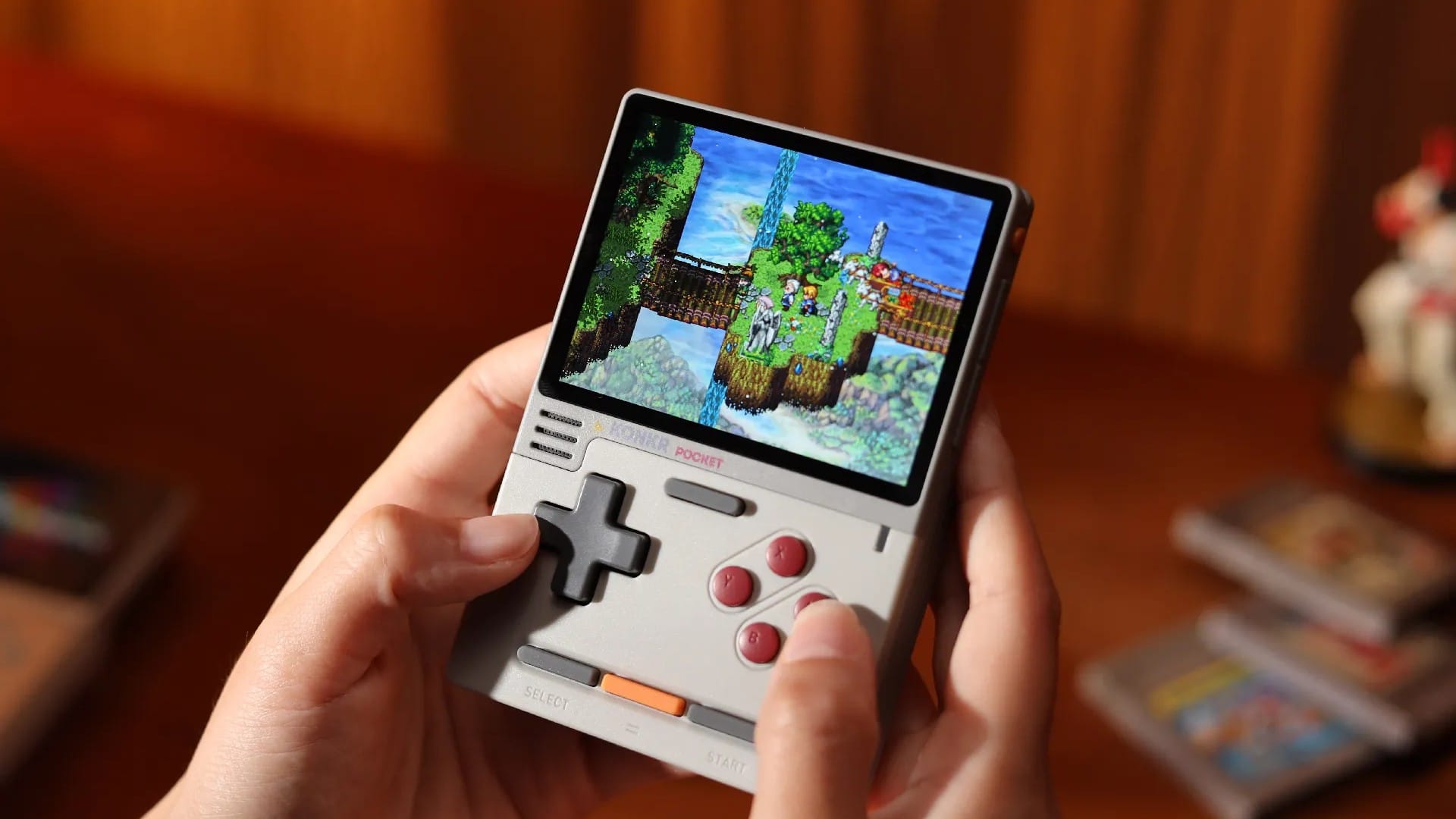 Hands holding a grey KONKR Pocket Block playing a pixel-art game
