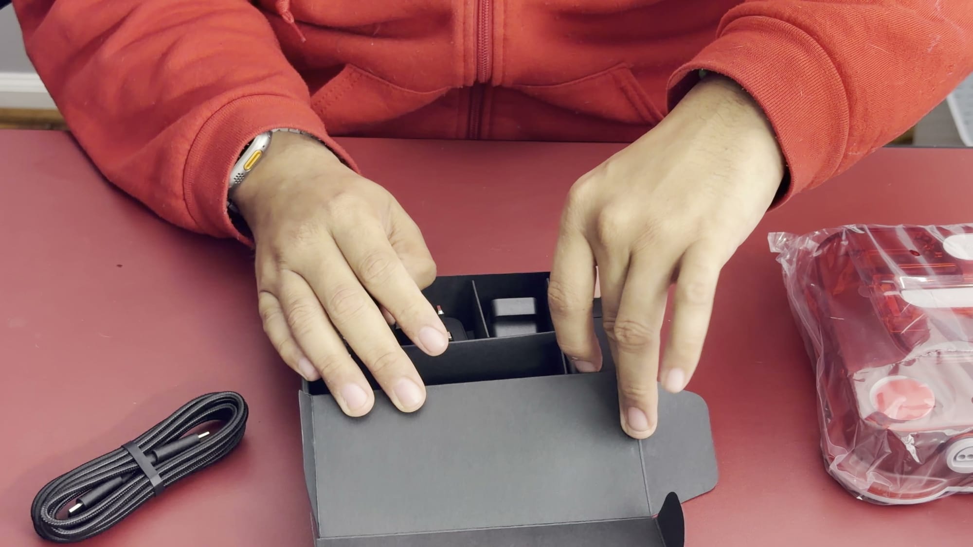 The opened ModRetro M64 box tray with a USB-C cable beside it on a red mat