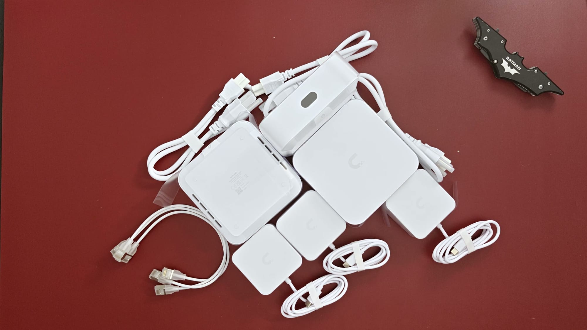 The UniFi Whole Home WiFi kit laid out: three Express 7 units, three power supplies and cables