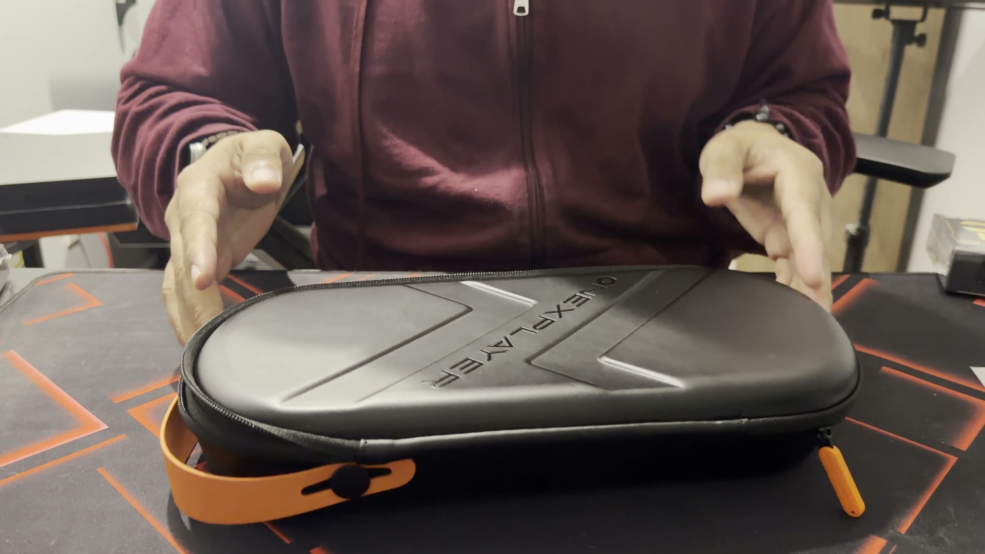 The OneXPlayer X2 Mini Pro carrying case, black with orange zipper pulls, on a desk
