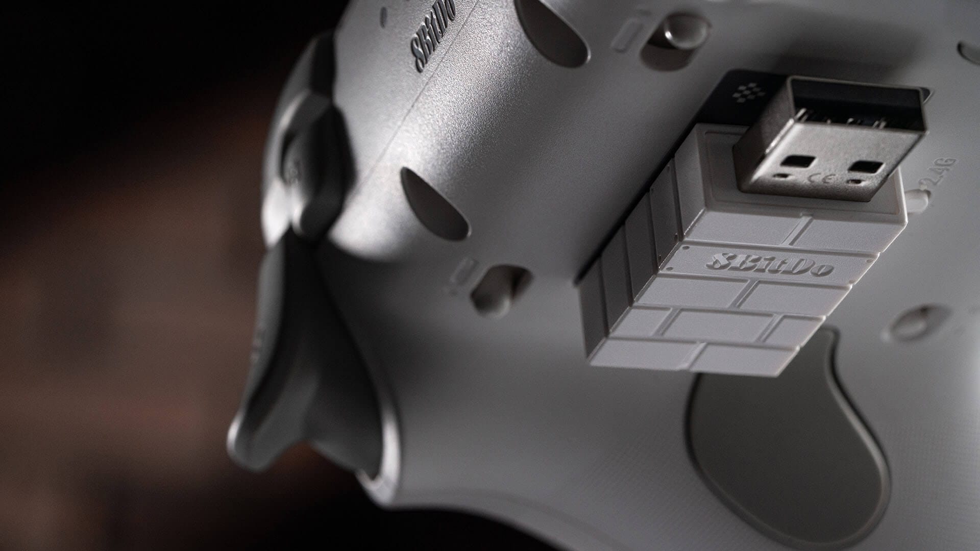 The 8BitDo 2.4G USB adapter held magnetically in a slot on the back of a white Ultimate 3C+