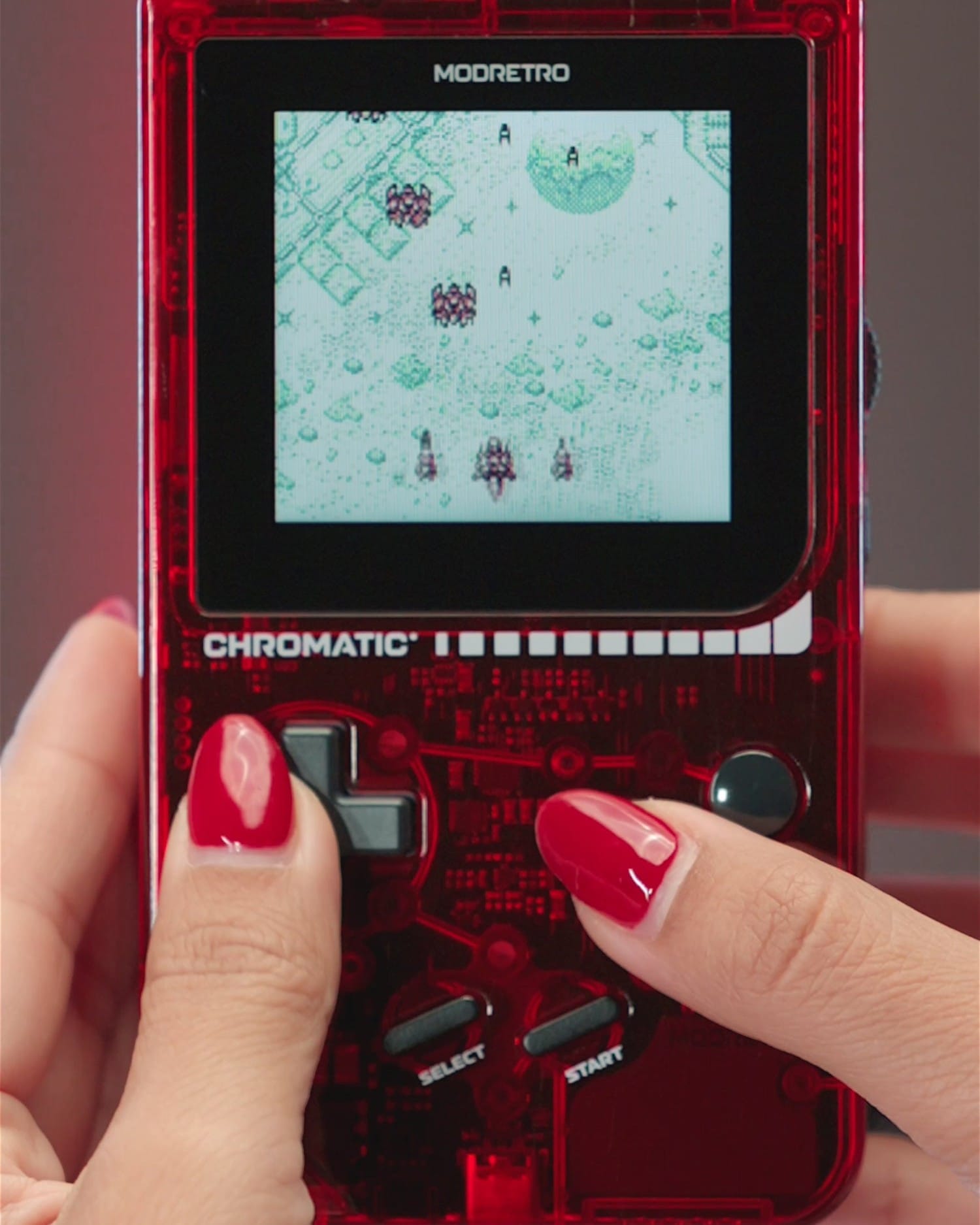 Hands holding the transparent red ModRetro Chromatic playing a Game Boy game
