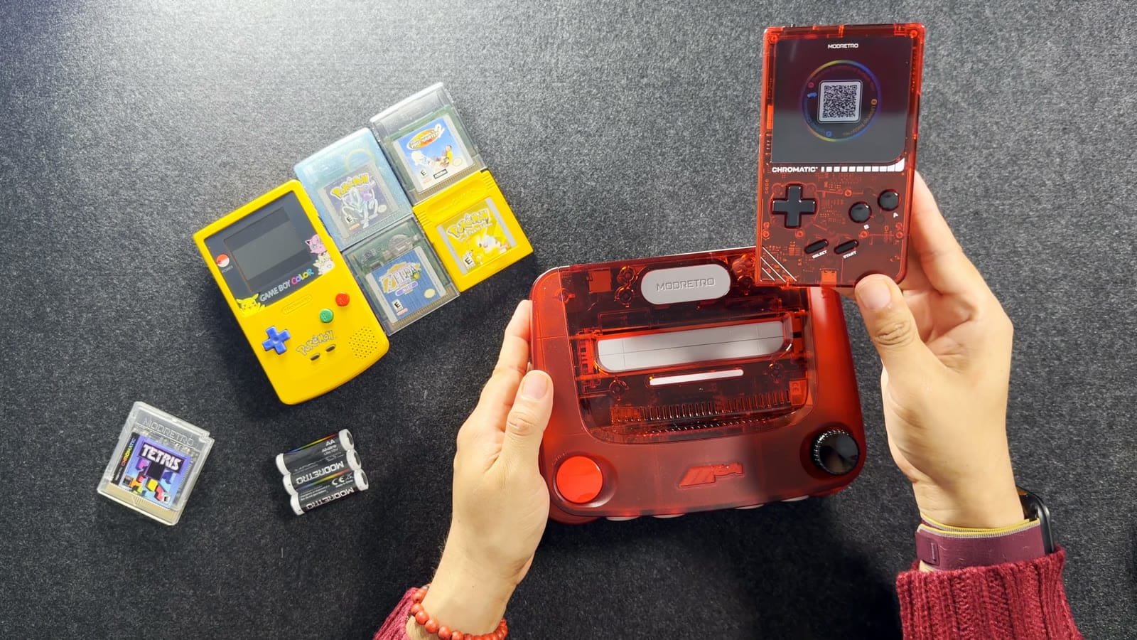 The transparent red Chromatic held up beside a transparent red ModRetro M64